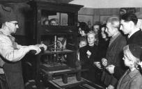 Een drukker in oorspronkelijke beroepskleding toont in 1947 hoe de Gutenberg-pers werkt. Foto: © Bundesarchiv